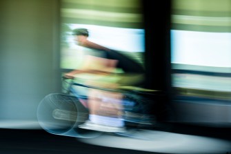 A time lapsed blurred photo of a person riding a bike.