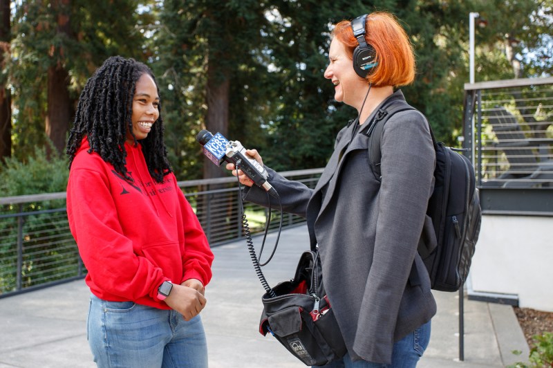 A journalist holding a microphone up to a student at the Oakland Opportunity Scholarships press conference.