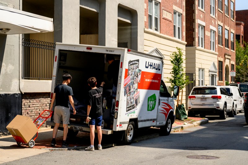 Two people unload a U-Haul truck in a Boston neighborhood.