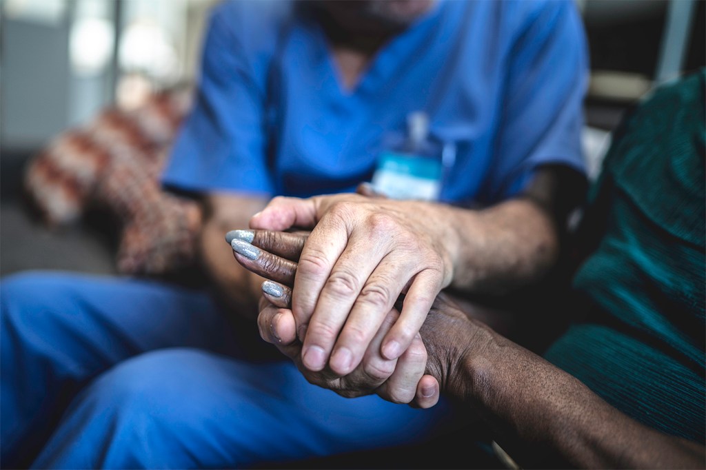 A nurse holding the hands of a patient.