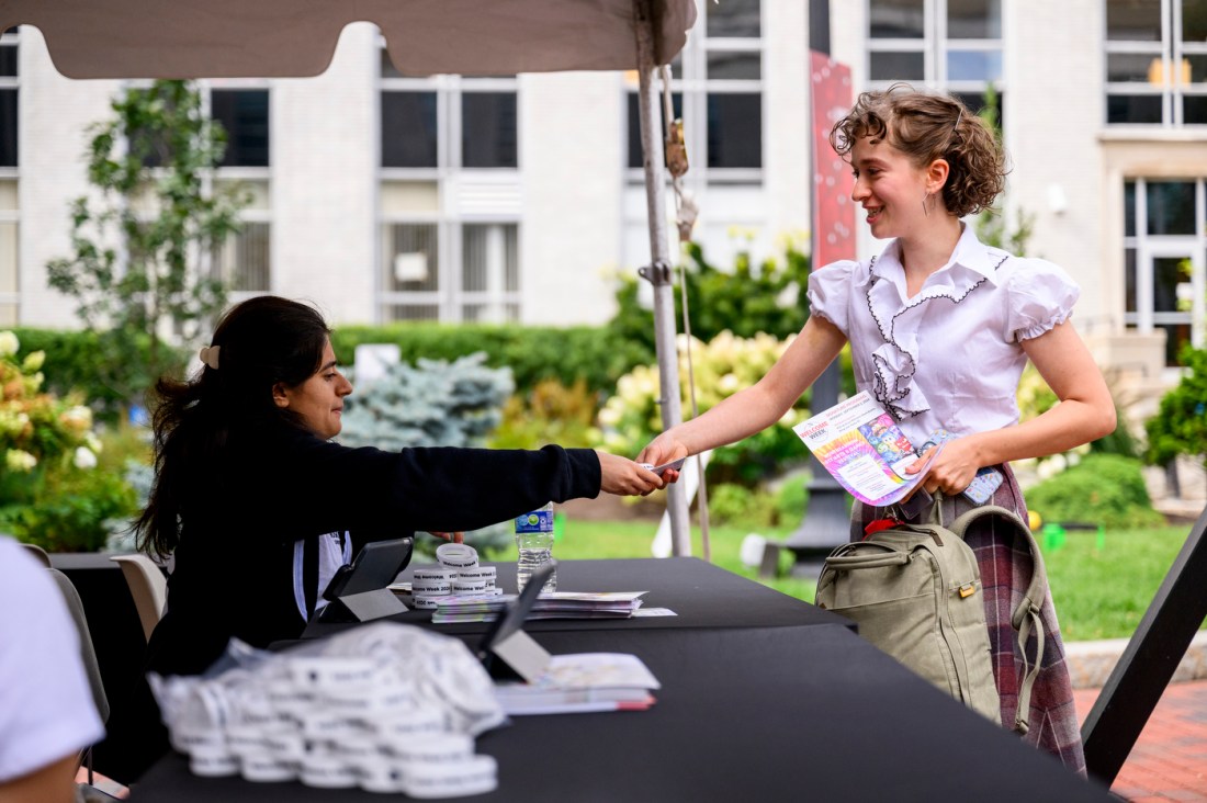 A student takes a pamphlet from someone sitting at a booth during Northeastern's Welcome Week.