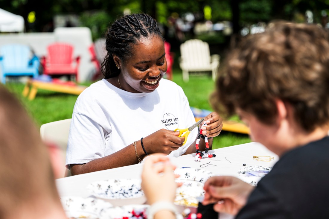 A person does arts and crafts at a table outside on a sunny day.