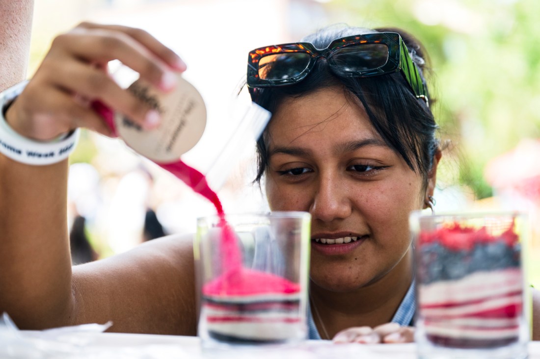 A person decorates sand art outside on a sunny day.