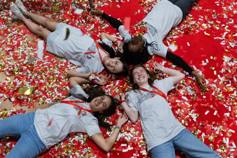 Students laying in confetti at Convocation.