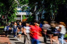 A blurred image of students walking along a path outside.