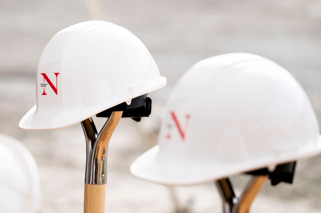 White hard hats with the Northeastern logo balanced on shovels at the Portland ground breaking. 