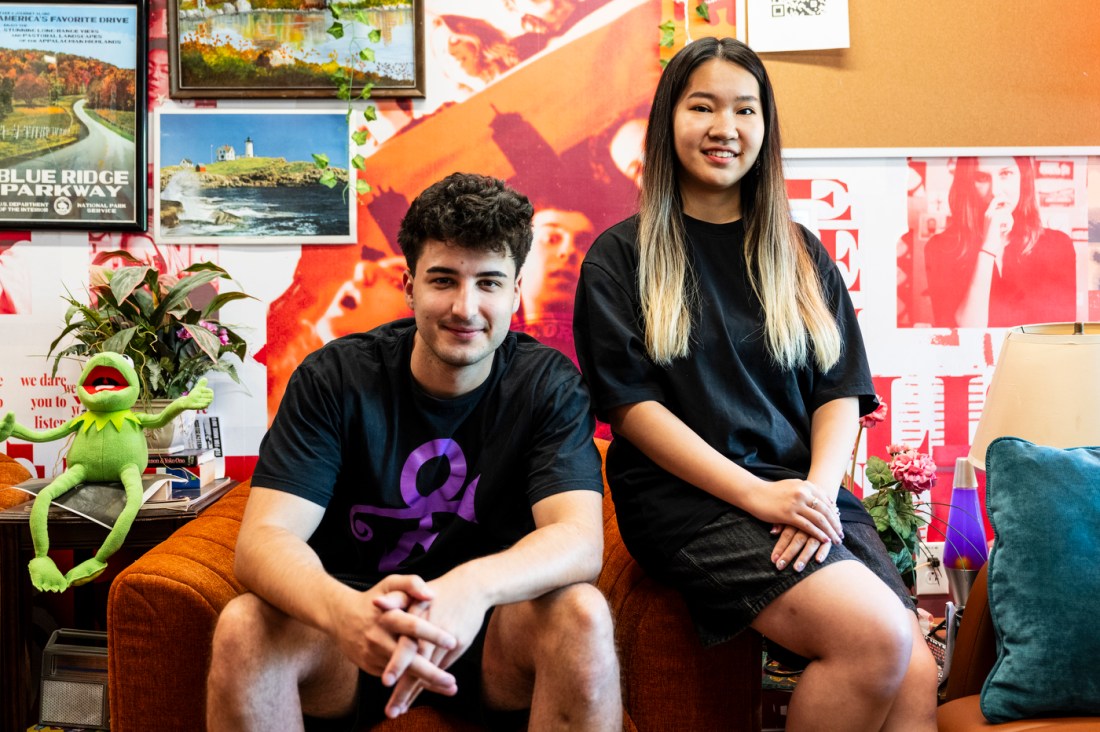 Jonathan Klopp sitting in an orange armchair and Michelle Wu sitting on the arm of the chair, both posing with their hands folded.