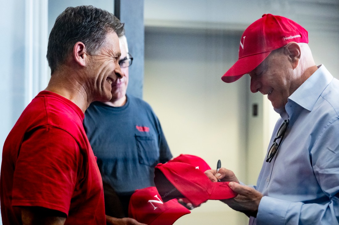 President Aoun signing a red baseball cap for a facilities worker. 