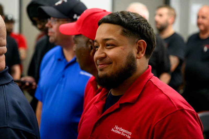 A person wearing a red collared shirt smiling at the facilities BBQ.