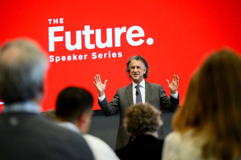 Daniel Levitin sitting on stage at the Presidential speaker series, gesturing with his hands. 