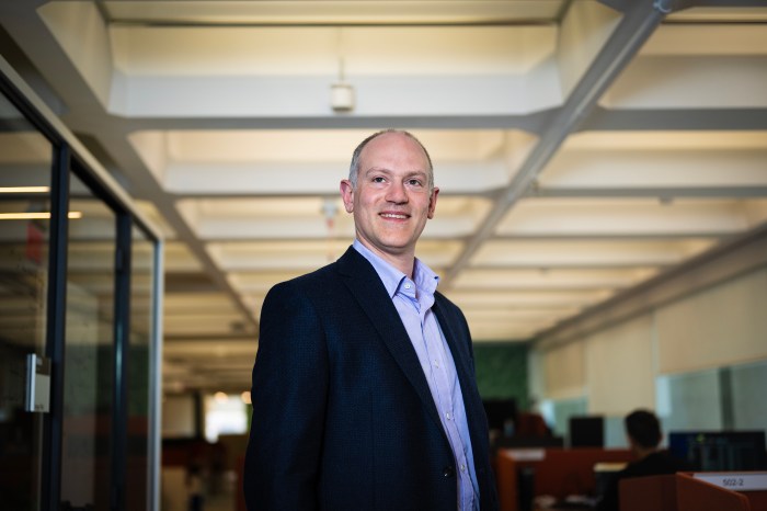 David Choffnes standing in a glass-walled office hallway.