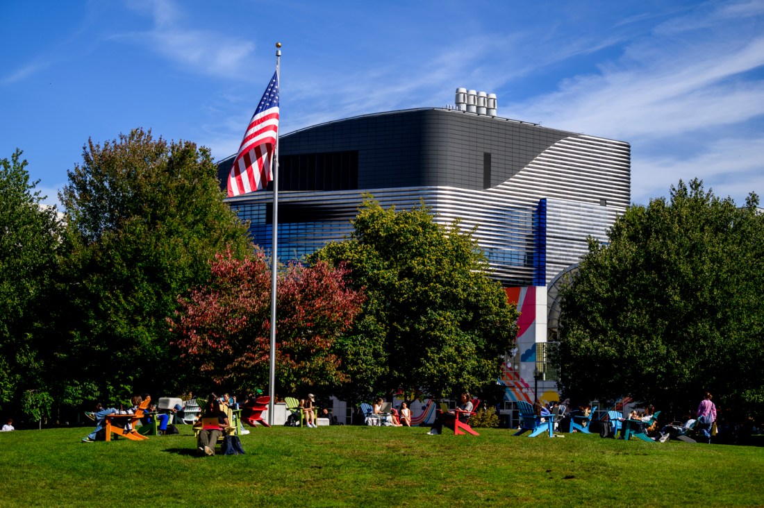 Students walking outside on a tree-lined campus pathway.