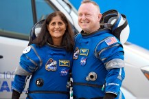 Astronauts Suni Williams and Butch Wilmore standing arm in arm smiling.