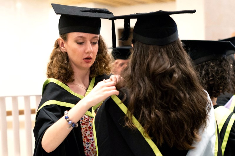 One graduate fixes another's gown.