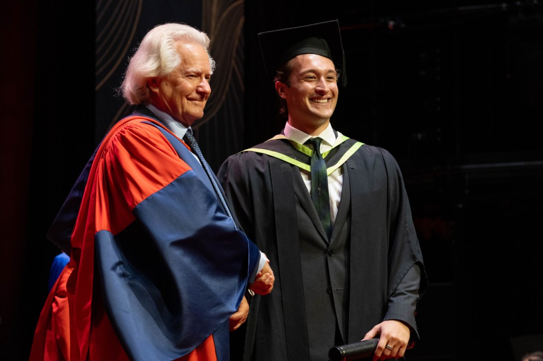 A graduate shaking the hand of Principal AC Grayling.