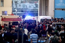 Ambulances with their lights on next to a crowd of people in Lebanon.