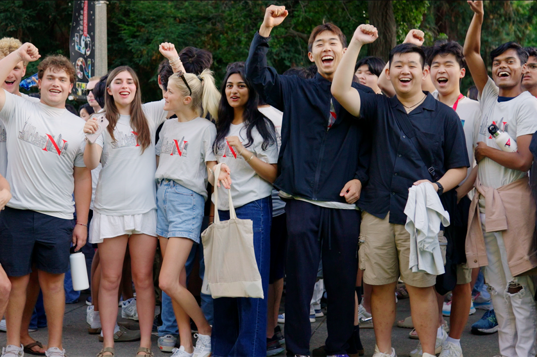 A group of students on the Oakland campus standing and cheering with their fists raised in the air.