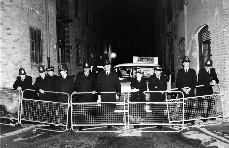 Police leaning on a barricade.