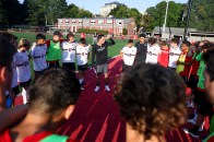 Jeremy Bonomo surrounded by soccer players on the field during a huddle.