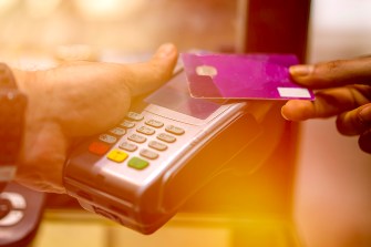 A pink credit card being tapped against a card reader.