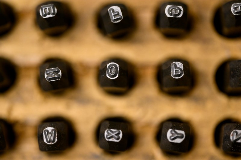 A set of metal stamps with letters arranged in a wooden holder.