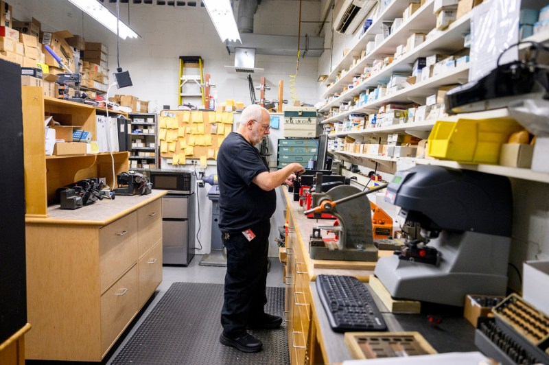 Person working in a workshop filled with various tools and shelves.