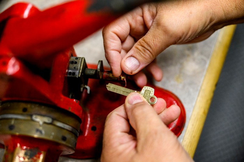 Hands working with a machine and a key in a close-up view.