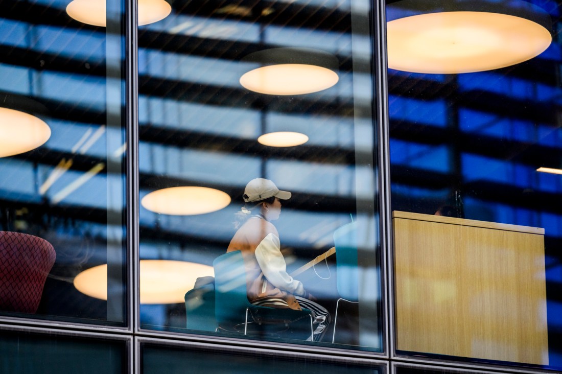 A student sits inside the ISEC building, seen through glass.