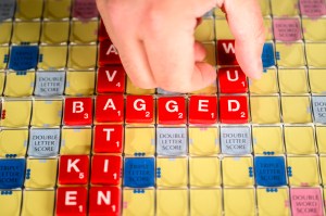 Bradley Whitmarsh arranging scrabble tiles on a board to spell the word 'bagged'.