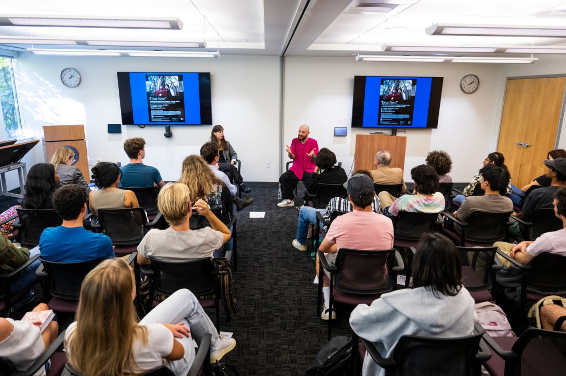 Stav Marin and Neta Weiner sitting at the fron tof a room for an event.