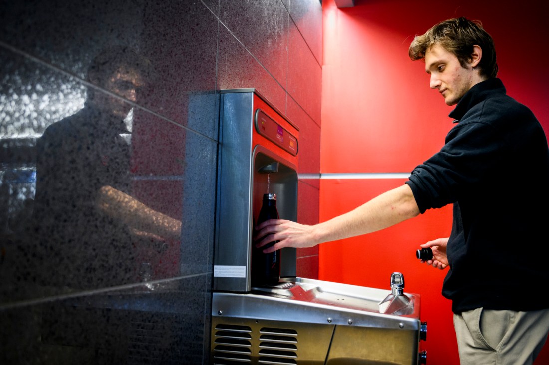 A person filling their reusable water at a water fountain station on campus.