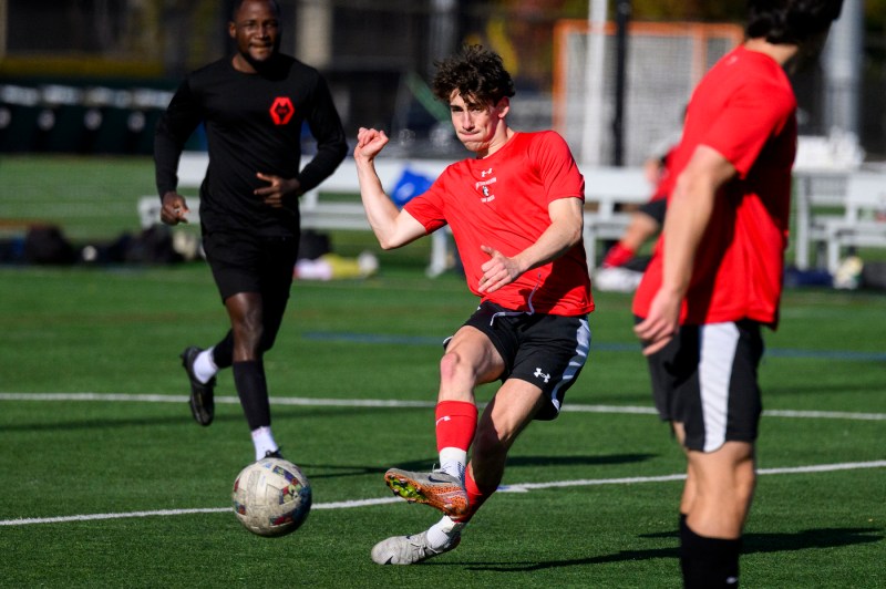 A player wearing a red t-shirt passing the soccer ball.