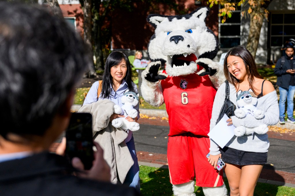 Two people posing with Paws, the Northeastern husky mascot.