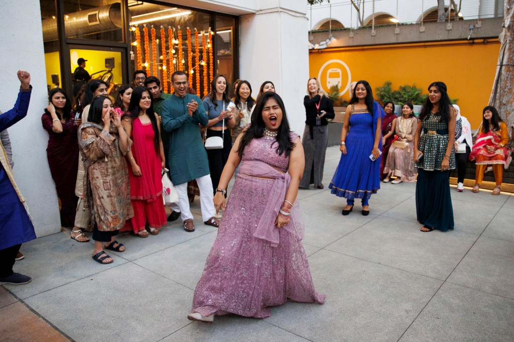 A person wearing a purple dress dances in a circle of other people.