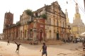 A building in Africa. Outside of the building, a kid does a cartwheel.