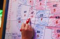 A hand holding a red sharpie coloring in a map of states in blue and red.