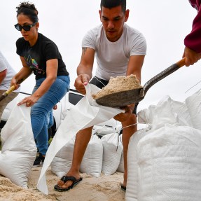 People on a beach collect sandbags.