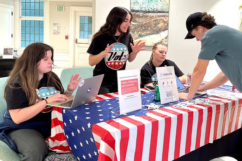 People sit at a voter registration table.