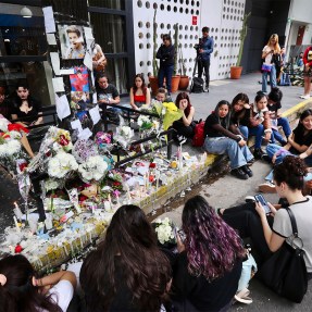 A group of fans sitting together in mourning for the death of Liam Payne.