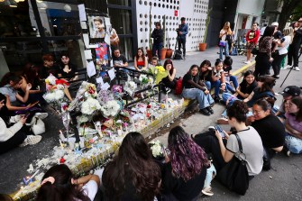 A group of fans sitting together in mourning for the death of Liam Payne.