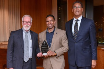 Mike Davis holding his award posing with two other people.