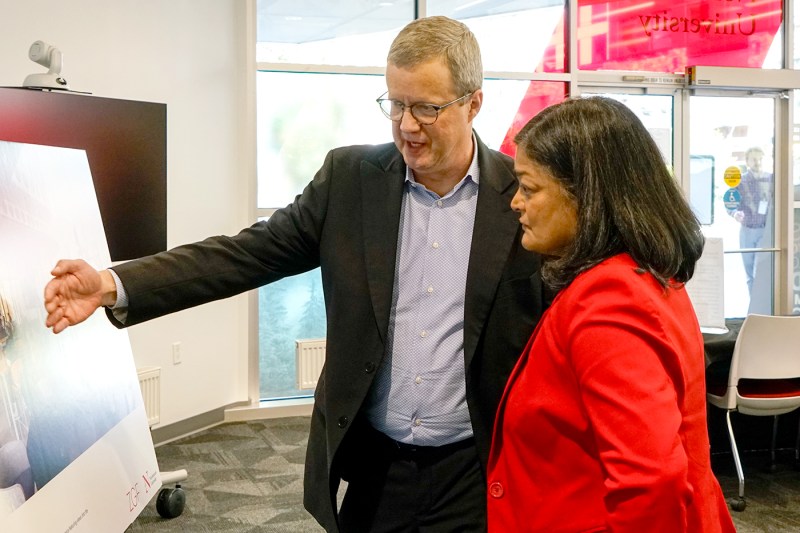 U.S. Rep. Pramila Jayapal standing next to Dave Thurman who is gesturing at an architectural rendering poster standing on an easel.