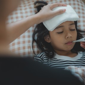 A person measuring a child's temperature.