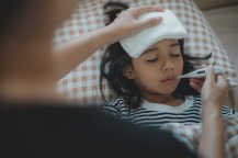 A person measuring a child's temperature.