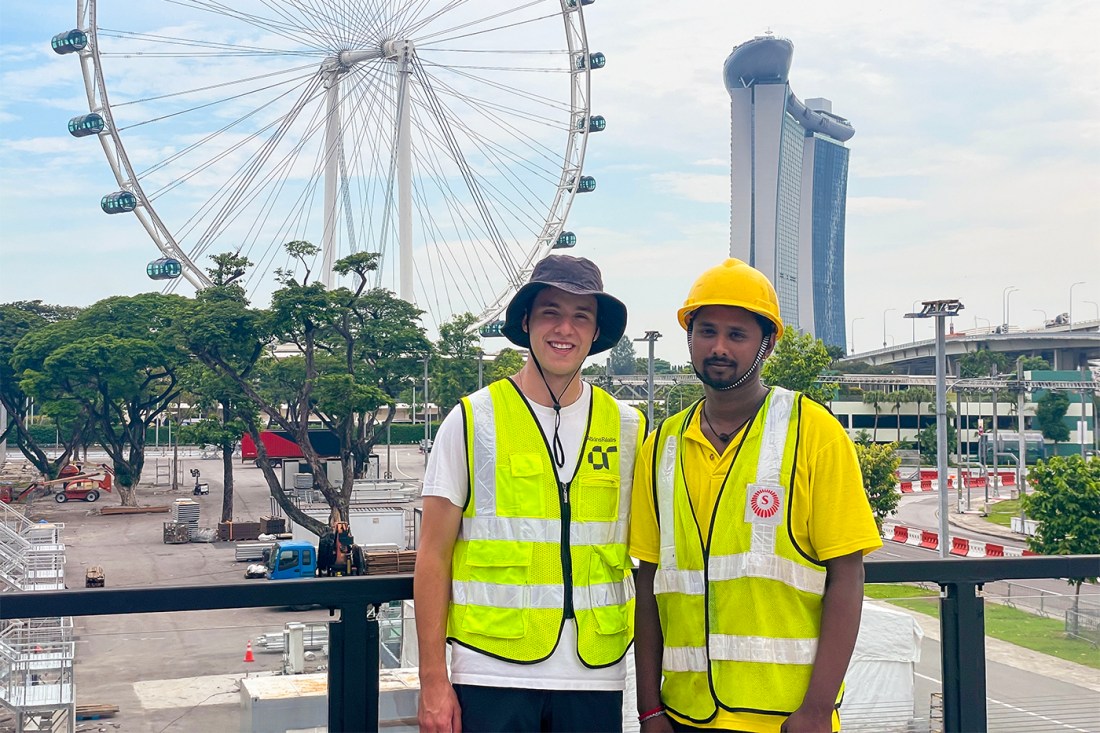 Fernando Alfaro and another person both posing at the Singapore Grand Prix in yellow vests.