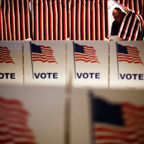 Polling booths are covered with prints of the American flag featuring the word 'VOTE' in blue.