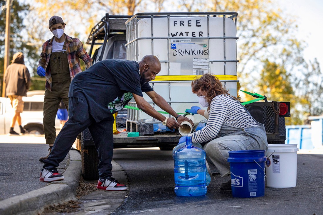 Volunteers filling up large blue bottles of drinking water.