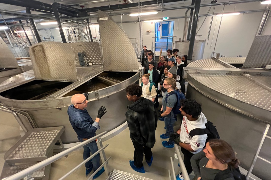 Students listening to an expert in a room with large steel vats.