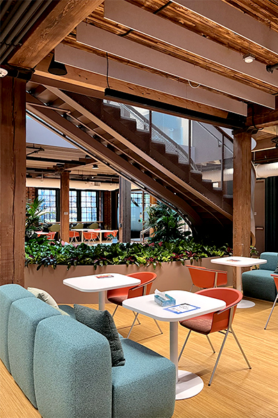 The interior of the new hub of the Seattle campus, with blue couches, white tables, and orange chairs. 