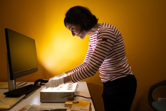 Irene Gates looking through archival slides and photographs.